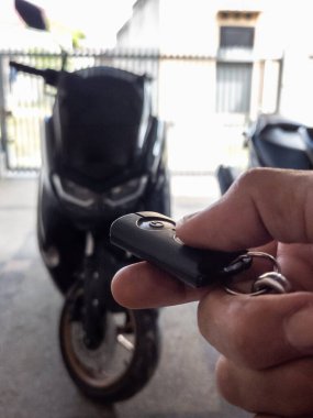 Modern bir scooter 'ın kilidini açmak için motosikletin anahtarlığını kullanan kişi.