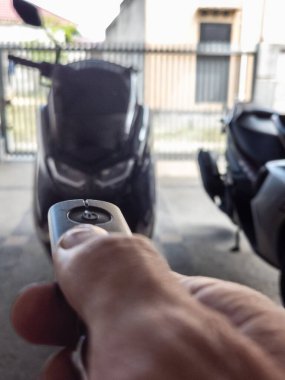 Modern bir scooter 'ın kilidini açmak için motosikletin anahtarlığını kullanan kişi.