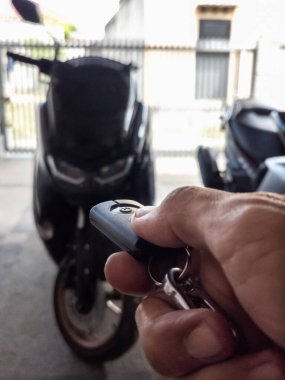 Modern bir scooter 'ın kilidini açmak için motosikletin anahtarlığını kullanan kişi.