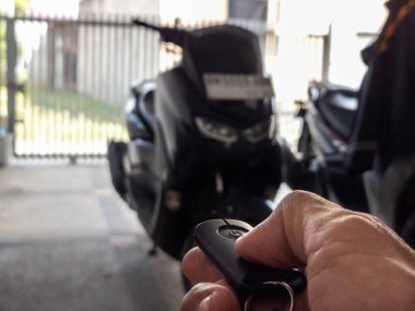 Modern bir scooter 'ın kilidini açmak için motosikletin anahtarlığını kullanan kişi.