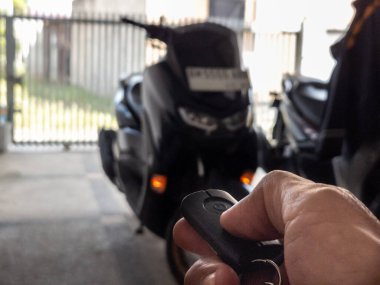 Modern bir scooter 'ın kilidini açmak için motosikletin anahtarlığını kullanan kişi.
