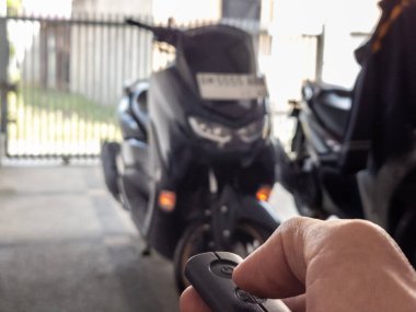 Modern bir scooter 'ın kilidini açmak için motosikletin anahtarlığını kullanan kişi.