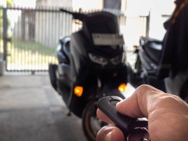 Modern bir scooter 'ın kilidini açmak için motosikletin anahtarlığını kullanan kişi.