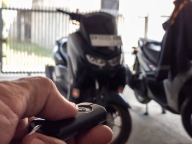 Modern bir scooter 'ın kilidini açmak için motosikletin anahtarlığını kullanan kişi.