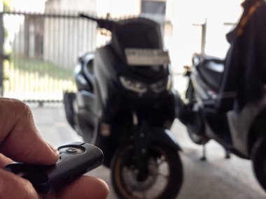 Modern bir scooter 'ın kilidini açmak için motosikletin anahtarlığını kullanan kişi.