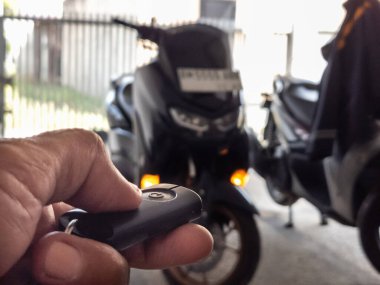 Modern bir scooter 'ın kilidini açmak için motosikletin anahtarlığını kullanan kişi.