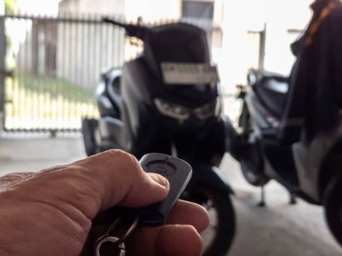 Modern bir scooter 'ın kilidini açmak için motosikletin anahtarlığını kullanan kişi.
