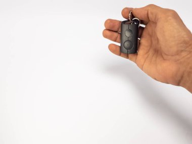 Yakın çekim bir elin siyah bir arabanın anahtarlığını tuttuğunu gösteriyor. Metal bir anahtarlık. El, çerçevenin sağ tarafında sade beyaz bir arka plana karşı konumlandırılmıştır. Resim, metin ya da tasarım ögeleri için geniş bir kopyalama alanına sahip, Varvari için ideal