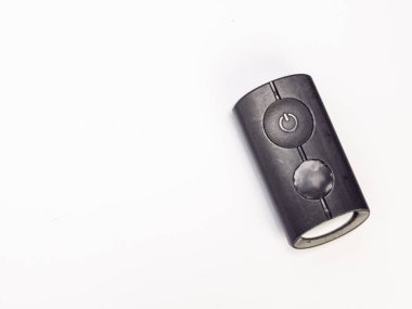 Beyaz arka planda siyah bir uzaktan kumandanın yukarıdan aşağı görüntüsü. Kumandanın iki dairesel düğmesi ve bir güç düğmesi sembolü var. Tasarım, sadelik ve işlevselliğe odaklı zarif ve modern. Görüntü iyi aydınlatılmış ve arka plan da... 