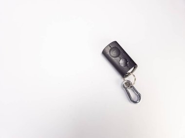 Siyah bir arabanın anahtarlığının gümüş bir karabinalı şarjörüyle yakın plan bir fotoğrafı. Anahtarlığın iki tuşu var ve temiz, beyaz bir arka plana ayarlı. Görüntü, anahtarın parlak tasarımı ve işlevsel yönlerini vurgular. Kompozisyon basit.,