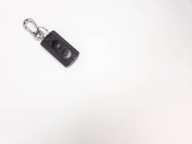 Üzerinde gümüş bir karabina klipsi olan siyah bir arabanın yakın çekim stüdyosu. Anahtarlığın iki tuşu var. Arka plan bembeyaz, temiz ve minimalist bir estetik oluşturuyor. Görüntü iyi aydınlatılmış, anahtar anahtarlığının detaylarını gösteriyor.