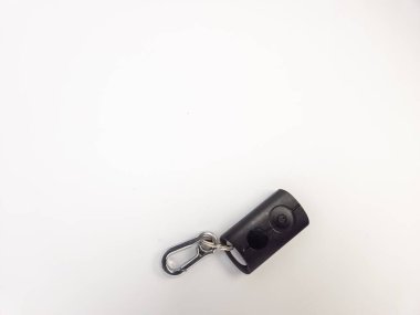 Siyah bir uzaktan kumandanın gümüş bir anahtarlıkla yakın çekim çekimi. Uzaktan kumandanın iki tuşu ve bir güç sembolü var. Arka plan düz beyaz. Görüntü iyi aydınlatılmış ve uzaktan kumanda ve anahtarlığın detaylarına odaklanmış durumda..