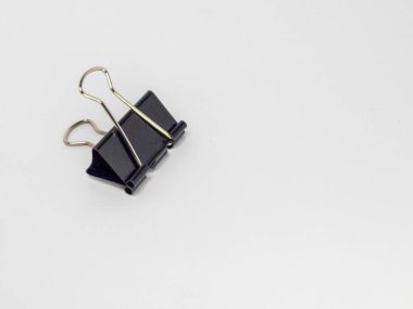 Sade beyaz bir arkaplanda duran siyah bir klasörün yakın plan fotoğrafı. Şarjör odak noktasında, metalik sapını ve siyah açısal gövdesini vurguluyor. Görüntü net ve basit, nesnenin biçimini ve işlevini vurguluyor..