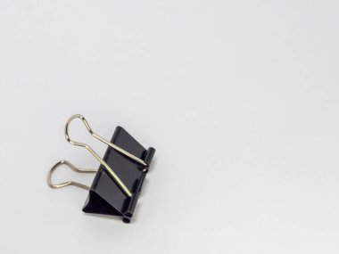 Sade beyaz bir arkaplanda duran siyah bir klasörün yakın plan fotoğrafı. Şarjör odak noktasında, metalik sapını ve siyah açısal gövdesini vurguluyor. Görüntü net ve basit, nesnenin biçimini ve işlevini vurguluyor..