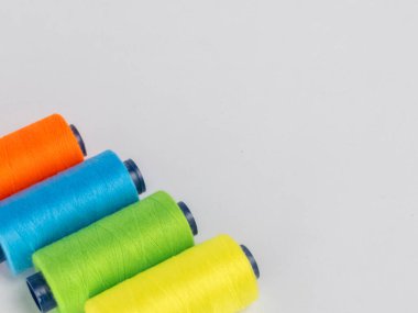 Resim dört iplik makarasına canlı renkte sahiptir: turuncu, yeşil, mavi ve sarı. Çapraz olarak temiz beyaz bir arkaplanda dizilmişler. Spikerler koyu mavi çekirdekli silindirik..