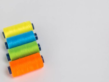 Resim dört iplik makarasına canlı renkte sahiptir: turuncu, yeşil, mavi ve sarı. Çapraz olarak temiz beyaz bir arkaplanda dizilmişler. Spikerler koyu mavi çekirdekli silindirik..