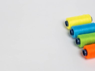 Resim dört iplik makarasına canlı renkte sahiptir: turuncu, yeşil, mavi ve sarı. Çapraz olarak temiz beyaz bir arkaplanda dizilmişler. Spikerler koyu mavi çekirdekli silindirik..