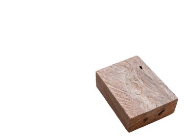 Yıpranmış, dikdörtgen ahşap bir bloğun temiz beyaz bir zemin üzerinde izole edilmiş yakın plan çekimi. Bloğun yüzeyi karmaşık ahşap desenler, dokular ve küçük delikler gösteriyor ki doğal olarak aşınmış.. 