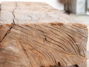 Yıpranmış ahşap bir kirişin detaylı bir yakın çekimi, odunun doğal dokularını ve desenlerini gösteriyor. Görüntü tahılları, çatlakları ve kusurları vurguluyor, yaş ve kırsal bir cazibe hissi yaratıyor.. 