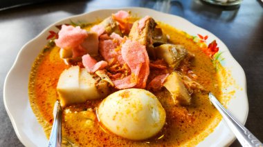 Pirinç kekleri (lontong), sebzeler ve hindistan cevizi sütü bazlı zengin köri içeren geleneksel bir yemek olan Endonezya Lontong Sayur 'unun yakın plan çekimi. Tabak haşlanmış yumurta ve pembe krakerle süslenmiş.. 