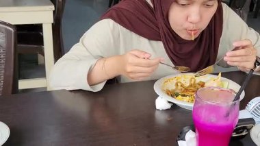 Renkli içeceklerle restoranda lezzetli yemekler yiyen bir kadın.