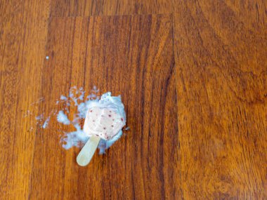 Tepetaklak bir çekim, yere dökülen dondurmayı ahşap bir zeminde yakalar ve ortalığı karıştırır. Donmuş şeker eridi, yapışkan bir su birikintisi ve ahşap bir sopa bıraktı..