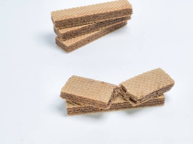 Bu stüdyo çekiminde düz beyaz arka planda bir yığın çikolatalı gofret var. Görüntü, çerezlerin dokusunu ve katmanlarını cazip çikolata dolgusuna odaklanarak sergiliyor. Gıda ile ilgili projeler için ideal.