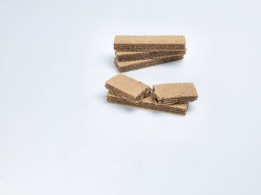 Yakından çekilmiş bir fotoğrafta, temiz beyaz bir arkaplanda ustalıkla yerleştirilmiş lezzetli çikolatalı gofret kurabiyeleri sergileniyor. Resim, yiyecek öğesini vurgulayan basit bir kompozisyon ile, gofretlerin dokusunu ve detaylarını vurgular..