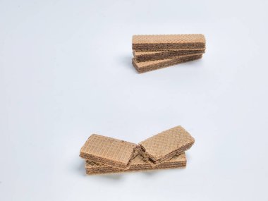 Bu resimde el değmemiş beyaz bir zemin üzerine yerleştirilmiş çikolata parçacıkları sergileniyor. Gofretlerin dokusuna ve cazibesine odaklanarak, katmanlı yapılarına ve çikolata dolgusuna dikkat çekiliyor..