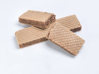 Sade beyaz arka planda birkaç çikolatalı gofret kurabiyesinin yakın plan çekimi. Kurabiyeler dikdörtgen şeklinde ve yüzeyinde waffle deseni var. Renk paletine kahverengi ve beyaz tonları hakim..