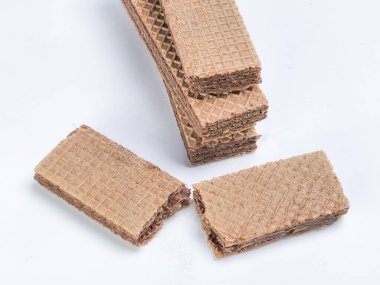 Yakın çekim bir stüdyo çekiminde beyaz arka planda bir yığın çikolatalı gofret kurabiyesi bulunur. İki gofret ayrılmış, biri kırılmış. Görüntü gofretlerin dokusunu ve katmanlarını gösteriyor, çikolata dolgusuna odaklanarak..