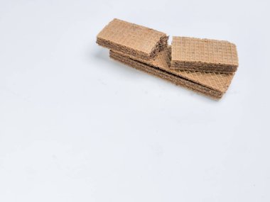 Yakın çekim bir stüdyo çekiminde beyaz arka planda yığılmış birkaç çikolatalı gofret yer alır. Gofretler dokulu bir yüzeye sahip dikdörtgen şeklindedir. Resim parlak bir şekilde ışıklandırılmış, gofretlerin rengini ve dokusunu vurguluyor.