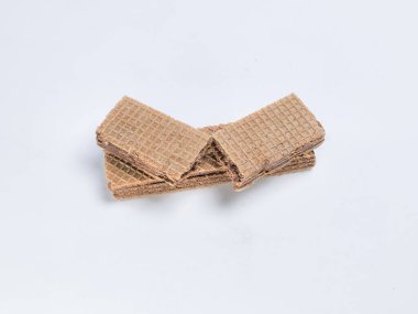 Yakın çekim stüdyosu vitrinlere bir yığın çikolatalı gofret sergiliyor, temiz beyaz bir arka planda düzenleniyor. Gofretlerin dokusuna ve detaylarına odaklanarak gevrek gofret ve kremalı çikolatanın katmanlarını vurguluyoruz..