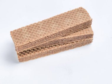 Yakın çekim bir stüdyo fotoğraf sergisi dikdörtgen çikolatalı gofretler yığını. Gofretler kremsi bir dolgu ile kaplı ve üst katmanın belirgin çapraz çatallı deseni var. Görüntü beyaz arkaplana karşı iyi ışıklandırılmış.