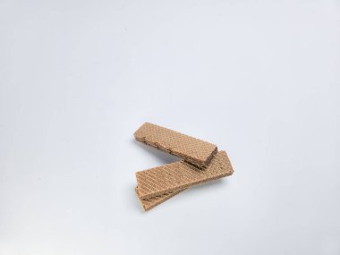 Beyaz arka planda iki çikolatalı gofretin yakın plan çekimi. Gofretlerin desenli bir yüzeyi ve zengin bir kahverengi rengi vardır. Kompozisyon basit ve temiz, ana konu olarak gofretleri vurguluyor..