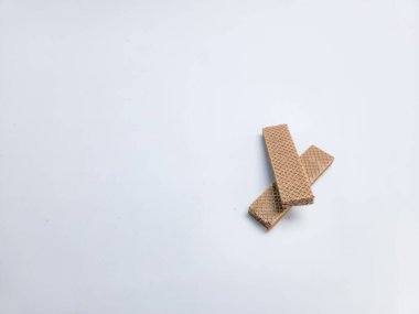 İki çikolatalı bisküvi düz beyaz arka planda çapraz olarak düzenlenir. Görüntü basit, temiz ve yukarıdan çekilmiş. Kurabiyeler odak noktasında, desen ve renklerini sergiliyorlar...