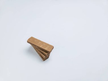 Bir yığın dikdörtgen çikolatalı gofret düz beyaz bir yüzeye çapraz olarak dizilmiş. Görüntü, gofretlerin dokusunu ve rengini vurgulayan yakın plan bir görüntüsünü içeriyor. Kompozisyon basit ve temiz, birincil konu gofretler..