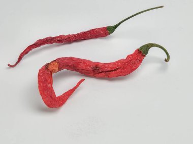Yakın çekim bir stüdyo çekiminde iki kırmızı kırmızı biber düz beyaz arka planda yer alır. Biberler kırış kırış ve koyu kırmızı saplı, yeşil saplı. Bir biber uzun ve düzdür, diğeri ise kıvrımlıdır..