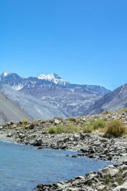 El Yeso Reservoir, And Dağları 'ndaki bir baraj boyunca saklanan yapay bir su deposudur. Nevado Piuquenes arka planda görülebilir.