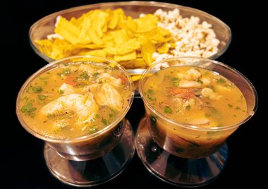 Ekvador ceviche 'sini balık ve karidesle karıştırmış, cam bardaklarda servis edilmiş, yanında da gevrek muz cipsi ve patlamış mısır. Geleneksel lezzet ve Ekvador kültürü kombinasyonu.