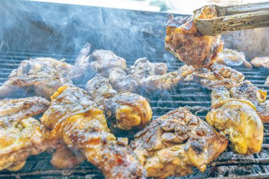 Izgara maşası kullanarak, ızgara tavuğu kızgın kömürlerin üzerinde çevirerek. Dumanın içinde leziz et parçaları ve ateş. Geleneksel bir yemek, aile toplantıları ve hafta sonları için mükemmel.. 