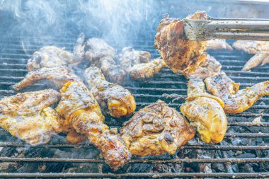 Izgara maşası kullanarak, ızgara tavuğu kızgın kömürlerin üzerinde çevirerek. Dumanın içinde leziz et parçaları ve ateş. Geleneksel bir yemek, aile toplantıları ve hafta sonları için mükemmel.. 