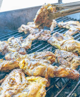 Izgara maşası kullanarak, ızgara tavuğu kızgın kömürlerin üzerinde çevirerek. Dumanın içinde leziz et parçaları ve ateş. Geleneksel bir yemek, aile toplantıları ve hafta sonları için mükemmel.. 