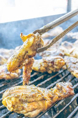 Izgara maşası kullanarak, ızgara tavuğu kızgın kömürlerin üzerinde çevirerek. Dumanın içinde leziz et parçaları ve ateş. Geleneksel bir yemek, aile toplantıları ve hafta sonları için mükemmel.. 