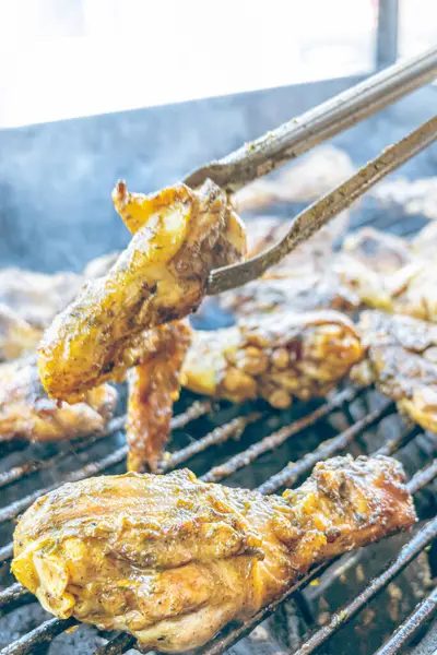 Izgara maşası kullanarak, ızgara tavuğu kızgın kömürlerin üzerinde çevirerek. Dumanın içinde leziz et parçaları ve ateş. Geleneksel bir yemek, aile toplantıları ve hafta sonları için mükemmel.. 