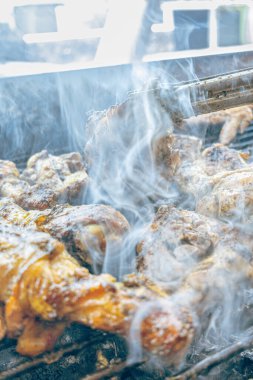 Izgara maşası kullanarak, ızgara tavuğu kızgın kömürlerin üzerinde çevirerek. Dumanın içinde leziz et parçaları ve ateş. Geleneksel bir yemek, aile toplantıları ve hafta sonları için mükemmel.. 