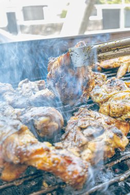 Izgara maşası kullanarak, ızgara tavuğu kızgın kömürlerin üzerinde çevirerek. Dumanın içinde leziz et parçaları ve ateş. Geleneksel bir yemek, aile toplantıları ve hafta sonları için mükemmel.. 