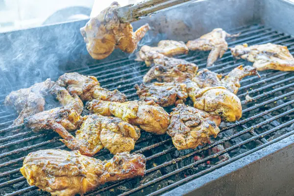 Izgara maşası kullanarak, ızgara tavuğu kızgın kömürlerin üzerinde çevirerek. Dumanın içinde leziz et parçaları ve ateş. Geleneksel bir yemek, aile toplantıları ve hafta sonları için mükemmel.. 