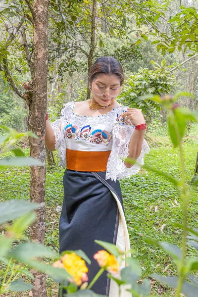 Doğayla uyum içinde Otavalo yerlisi bir kadın, anako, nakışlı bluz, altın walka kolye, renkli manila kuşağı ve manilla ya da bilezik takıyor..