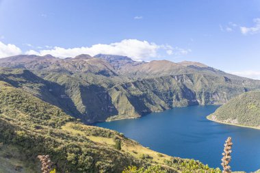 Cotacachi, Ecuador  August 5, 2025: Cuicocha Lagoon in the Ecuadorian Andes, surrounded by vegetation. In the background, the majestic Cotacachi Volcano with its summit hidden among the clouds.